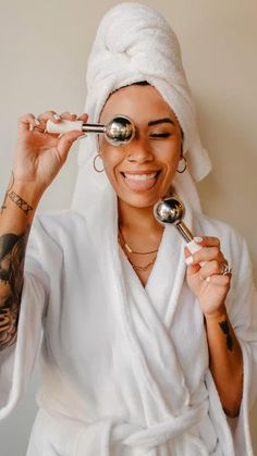 a woman with a towel on her head is holding two spoons in front of her face