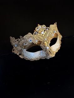 The cracked brocade lace design adds a touch of sophistication and the jewels are carefully placed to catch the light and enhance your beauty. Securely and comfortably fits every face shape so you can enjoy a perfect evening at the masquerade ball.

Age Group/Gender - Adult/Women

Size/Type - One size fits all adults

Mask Color - Gold

Mask Material - Polyresin/Fabric

Accent Material - Gems Elegant Embellished Gold Lace, Elegant Embellished Lace For Festive Occasions, Elegant Eye Mask For Masquerade, Elegant Silver Lace For Party, Elegant Silver Lace For Wedding, Vintage Gold Masquerade Mask For Party, Elegant Masquerade Mask For Festivals, Elegant Silver Masquerade Mask For Wedding, Elegant Eye Mask For Formal Masquerade