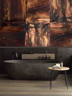 a bath tub sitting next to a wooden table in front of a painting on the wall