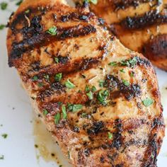 two pieces of grilled meat sitting on top of a white plate with parsley