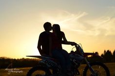 a man and woman are sitting on a dirt bike at sunset with the sun in the background