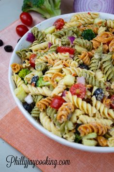 a bowl filled with pasta salad next to broccoli