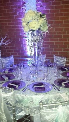 the table is set with purple and white plates, silver napkins, and flowers