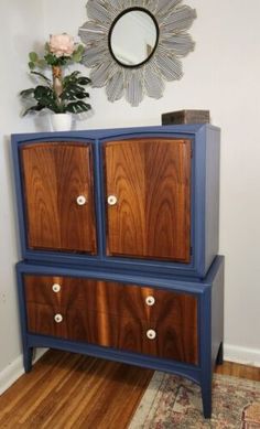 a blue and brown dresser sitting on top of a wooden floor next to a mirror