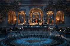 a fountain in front of a building with people standing around it and lights on the ceiling