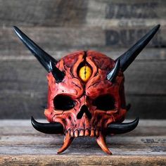 a skull mask with horns on it sitting on top of a wooden table next to a wall