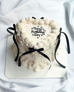 a heart shaped cake on a white plate with black ribbon and writing happy birthday you