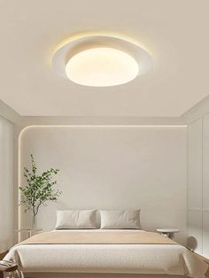 a bedroom with white walls and flooring has a round light fixture above the bed