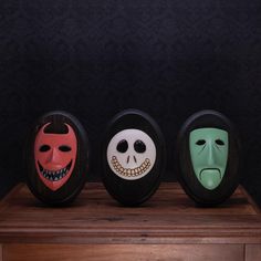 three different colored masks sitting on top of a wooden table