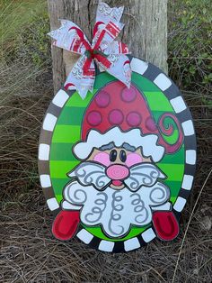 a wooden sign with a santa clause on it's face and a bow around its neck