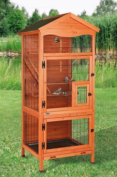 a large wooden bird cage in the grass