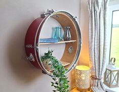 a round shelf with plants and vases on it next to a window sill