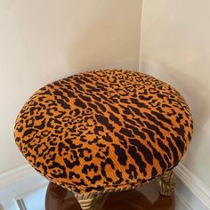 a leopard print ottoman sitting on top of a wooden table next to a white wall