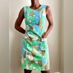 New Without Tags. Green, Blue, Creamy-Beige And Khaki Retro Floral Patterned Cotton Fabric With A Honeycomb Textured Finish. Sleeveless Design With Scoop Neckline And Concealed Back Zip Fastening. Flattering Deep, Fitted Empire-Line Waistband And Gently Flared Skirt Section With Large Side Pockets. Fully Lined Smoke Free. Pet Free. Vintage Cotton Sleeveless Dress, Sleeveless Retro Mini Dress With Retro Print, Retro Sleeveless Lined Dress, Vintage Sleeveless Beach Mini Dress, 1970s Style Sleeveless Cotton Dress, 1970s Sleeveless Cotton Dress, Mod Sleeveless Lined Dress, Vintage Sleeveless Mini Dress With Floral Print, Mid-century Sleeveless Cotton Dress