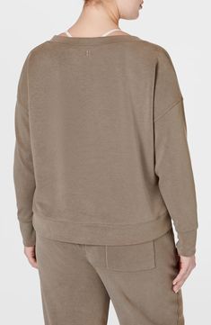 Scuba-textured fabric adds to the sporty-chic feel of a slightly cropped sweatshirt featuring a wide neck and thumbhole cuffs. 22" length (size Medium) Scoop neck Long sleeves with thumbhole cuffs 54% recycled polyester, 40% modal, 6% elastane Machine wash, tumble dry Imported