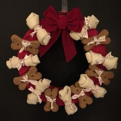 a wreath made out of teddy bears with red ribbon and bow hanging on the wall