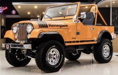 an orange jeep is parked in a showroom