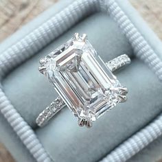 an emerald - cut diamond ring sits in a velvet box on top of a table