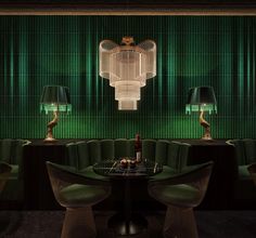 a table with two chairs and a wine bottle on it in front of a green wall