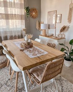 a dining room table and chairs in front of a window with curtains on the windowsill