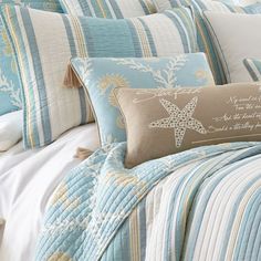 a bed covered in blue and white comforters with starfishs on the pillows