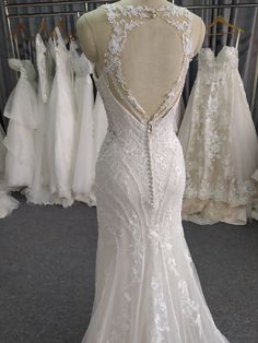 the back of a wedding dress on display in a bridal shop, with other gowns behind it