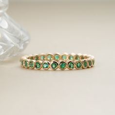 Nyra Timeless, elegant & dainty, this rich shade of green will make you feel like royalty each time you gaze at your hand! This can be your vibrant and unique wedding band, yet also the perfect dainty ring to add a pop of color to your solid gold ring stack. This is a full eternity band surrounding the entire finger. Choose your metal and size, and we will make it custom for you. May’s birthstone, this is a stunning ring to stack with your wife’s wedding ring! - Handmade- Solid Gold- Natural Emerald- Total Emerald Carat Weight: 1 ctw for size 6.5 ctw- Width of the Band: 2.5 mm - Height of the Band: 1.7 mm All pieces come beautifully boxed in suede pouches you can always use when traveling! Emerald Wedding Band Stack, Wedding Band With Emeralds, Green Emerald Wedding Band, Emerald Stone Wedding Band, Emerald Stacking Ring, Colorful Wedding Band, Emerald Green Wedding Band, Green And Gold Ring, Green Wedding Band