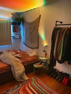 a bed room with a neatly made bed and lots of clothes hanging on the wall