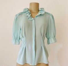 "Vintage 1960s feminine aqua top from Helena International, featuring exquisite retro detailing such as a ruffled collar, gentle pleating at the shoulders, front and back tucks for fabulous fit, and gathered sleeves ending at the elbow in ruffles. Hidden front button placket. Semi transparent. 100% polyester. Approximate Measurements: Chest: 36\"; Waist: Up to 29\"; Length: 22\" Labeled a size 6 Retro beauty, circa 1960s, is in excellent vintage condition, with no indication it was ever even wor Retro Beauty, Feminine Top, Gathered Sleeves, Ruffled Collar, Semi Transparent, Green Blouse, Womens Blouses, 1950s Vintage, Vintage 1960s