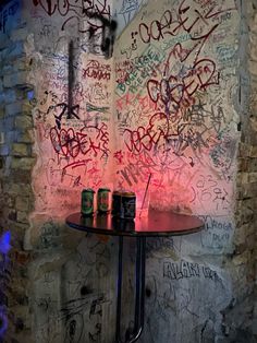 a table with two cans on it in front of a wall covered in grafitti