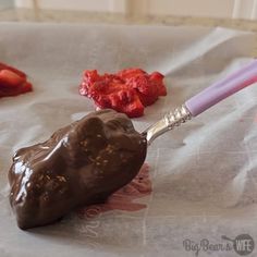 there is a spoon with chocolate on it next to strawberries