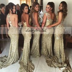 four women in gold dresses standing next to each other and looking at the same photo