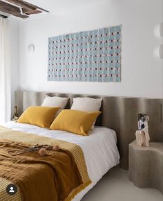 a bed with yellow and white pillows on top of it next to a dog statue