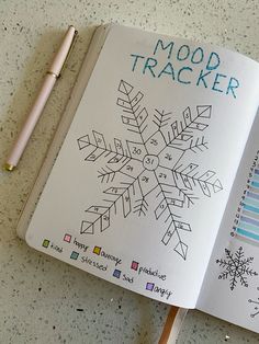 an open notebook with snowflakes drawn on it next to a pen and pencil