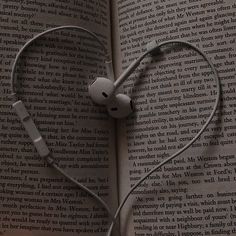 an open book with headphones in the shape of a heart on top of it