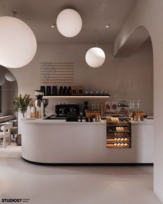 the interior of a coffee shop with white walls and round lights hanging from the ceiling