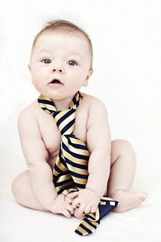 a baby wearing a tie sitting on the ground