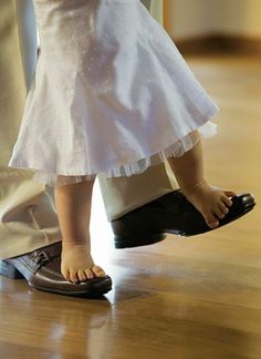 two people standing next to each other on top of a hard wood floor with their feet in the air