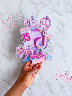 someone is holding up a pink and blue birthday card with the number fifteen on it