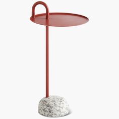 a red table with a white rock on the bottom and a metal stand in front