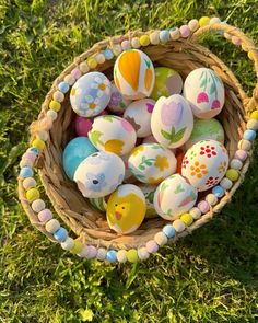 an easter basket filled with painted eggs in the grass on top of green grass covered ground