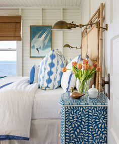 a blue and white bedroom with flowers on the nightstand