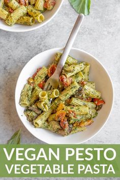 two bowls filled with pesto pasta on top of a white table next to a green leaf