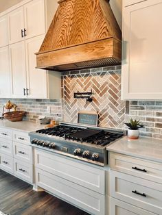 a stove top oven sitting inside of a kitchen next to white cupboards and drawers