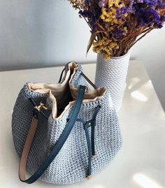 two purses sitting next to each other with flowers in the bag on the table