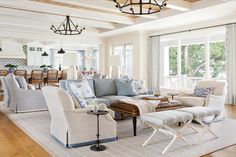 a living room with couches, chairs and lamps on the ceiling in front of windows