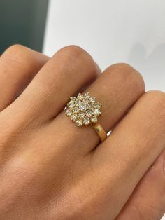 a woman's hand with a yellow gold ring and diamond flower design on it