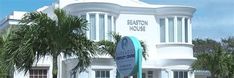 a white building with palm trees in front of it and a blue sign that says saffron house