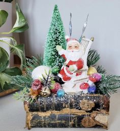 a santa clause figurine sitting on top of an old book surrounded by christmas decorations