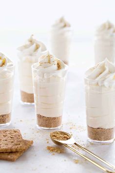 small desserts with whipped cream and graham crackers on a white countertop next to cookies